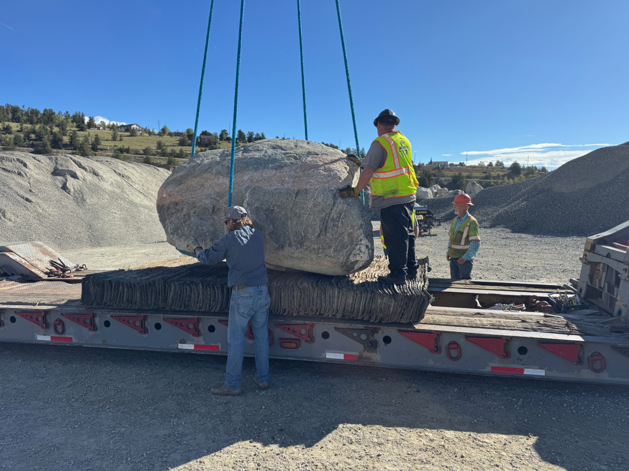 Crew setting boulder with crane